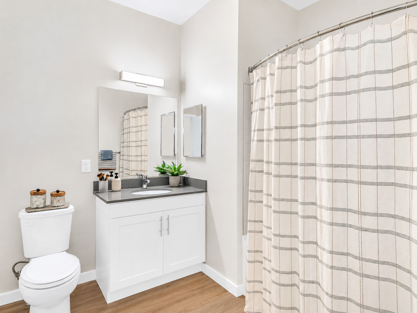 Bathroom with vanity, mirror, toilet, and striped shower curtain in a modern apartment.