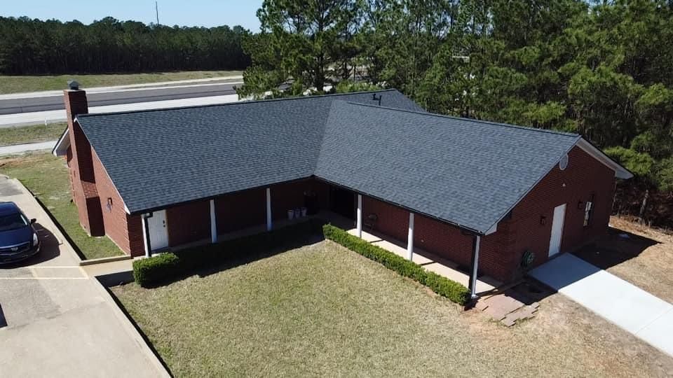 Brick house with dark roof and white trim, front porch, and driveway on a grassy lawn.