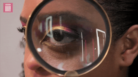 A woman is looking through a magnifying glass at her eye.