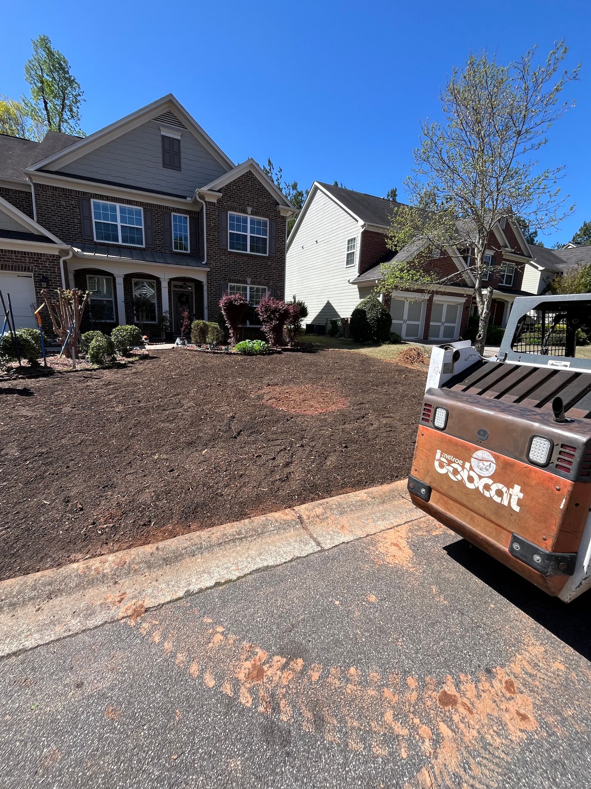 A bobcat tractor is parked in front of a house.