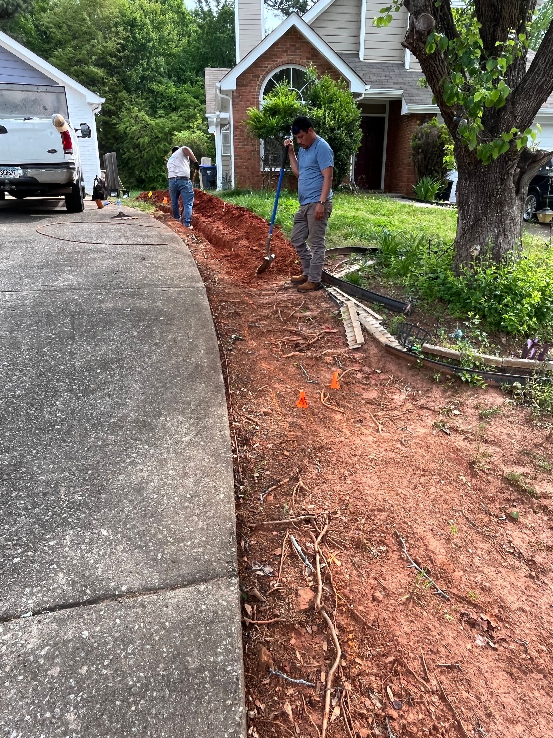 A group of men are working on a sidewalk in front of a house.