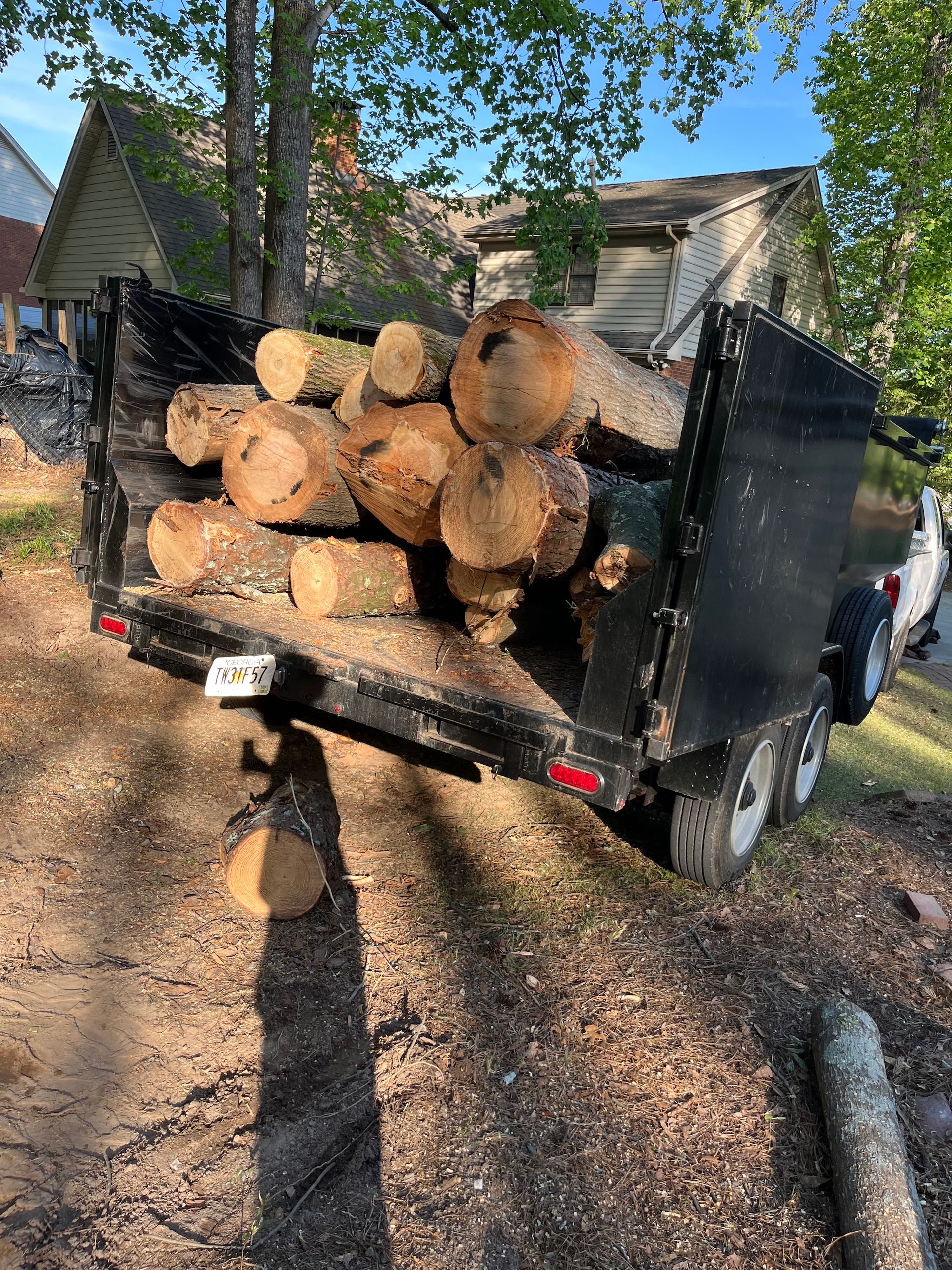 A trailer filled with logs is parked on the side of the road.