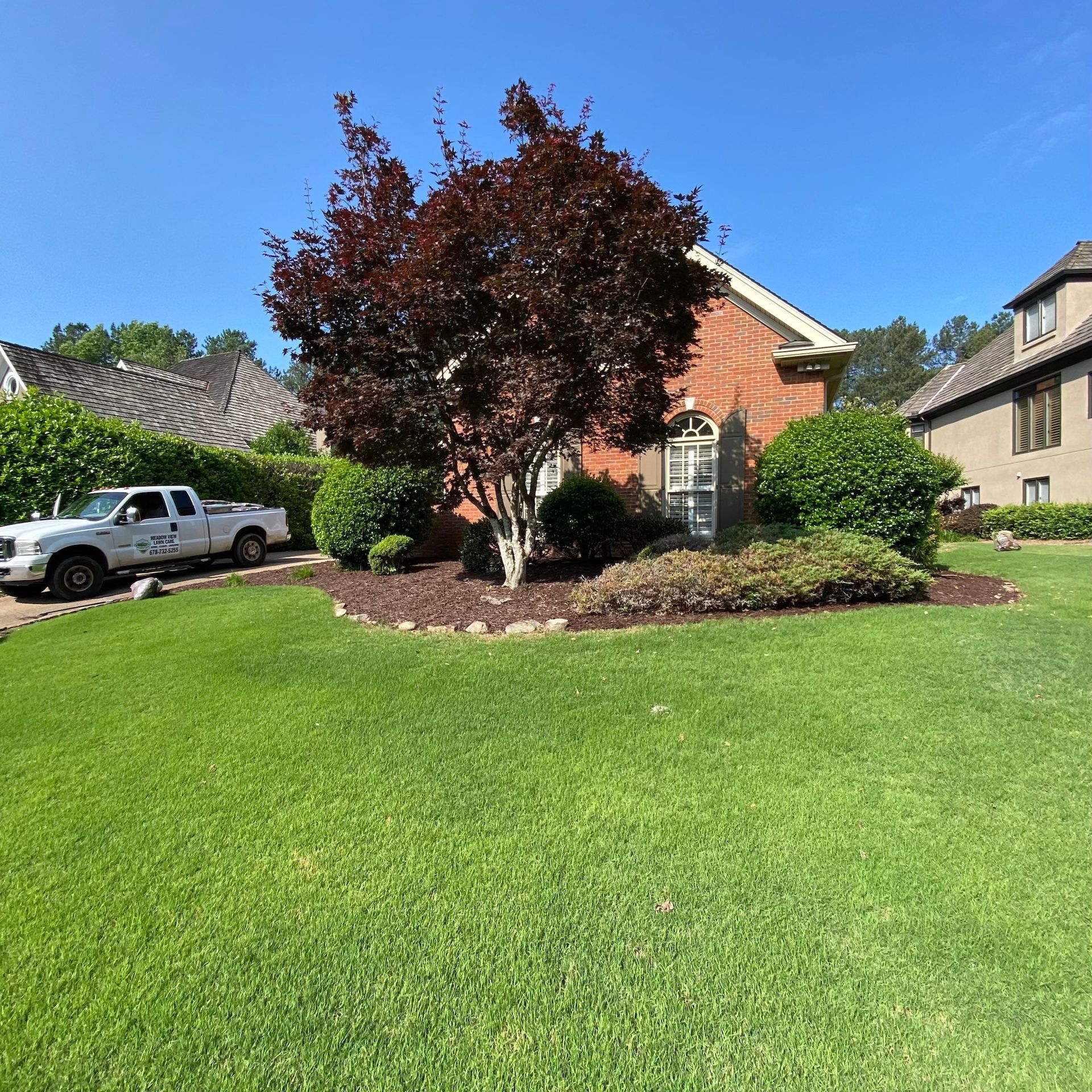 A white truck is parked in front of a brick house