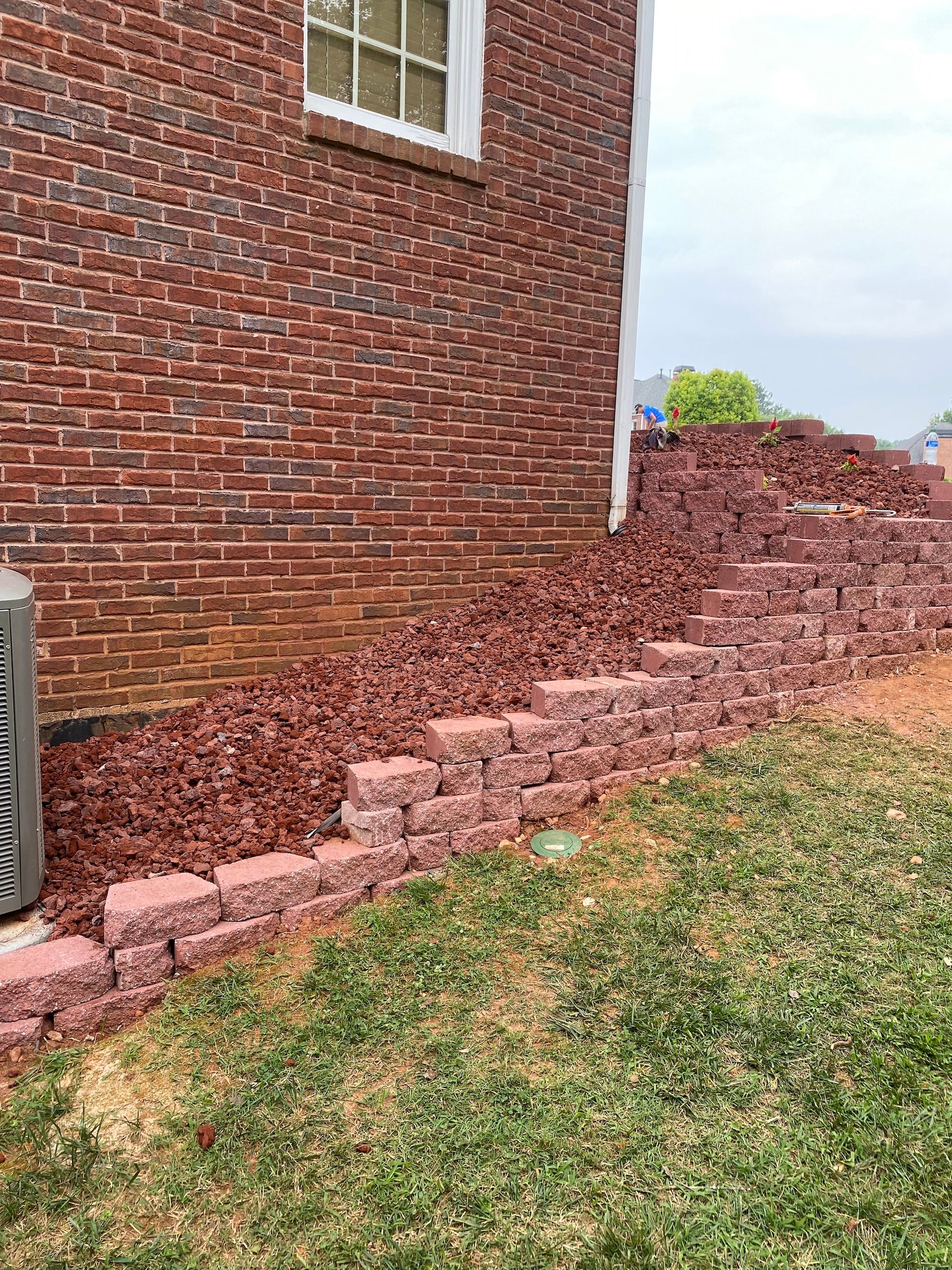 There is a brick wall in the backyard of a brick house.