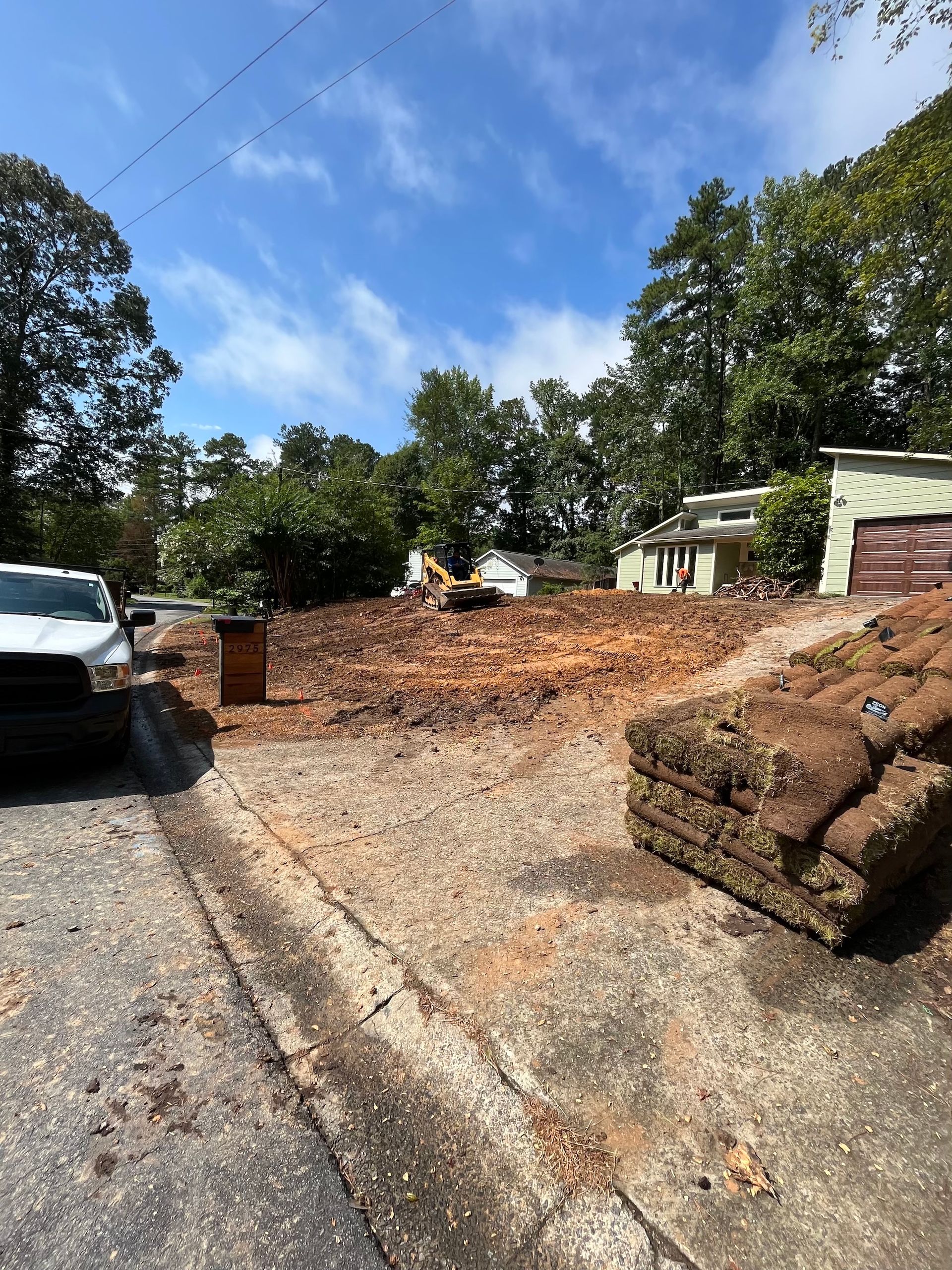 A white truck is parked on the side of the road next to a pile of grass.