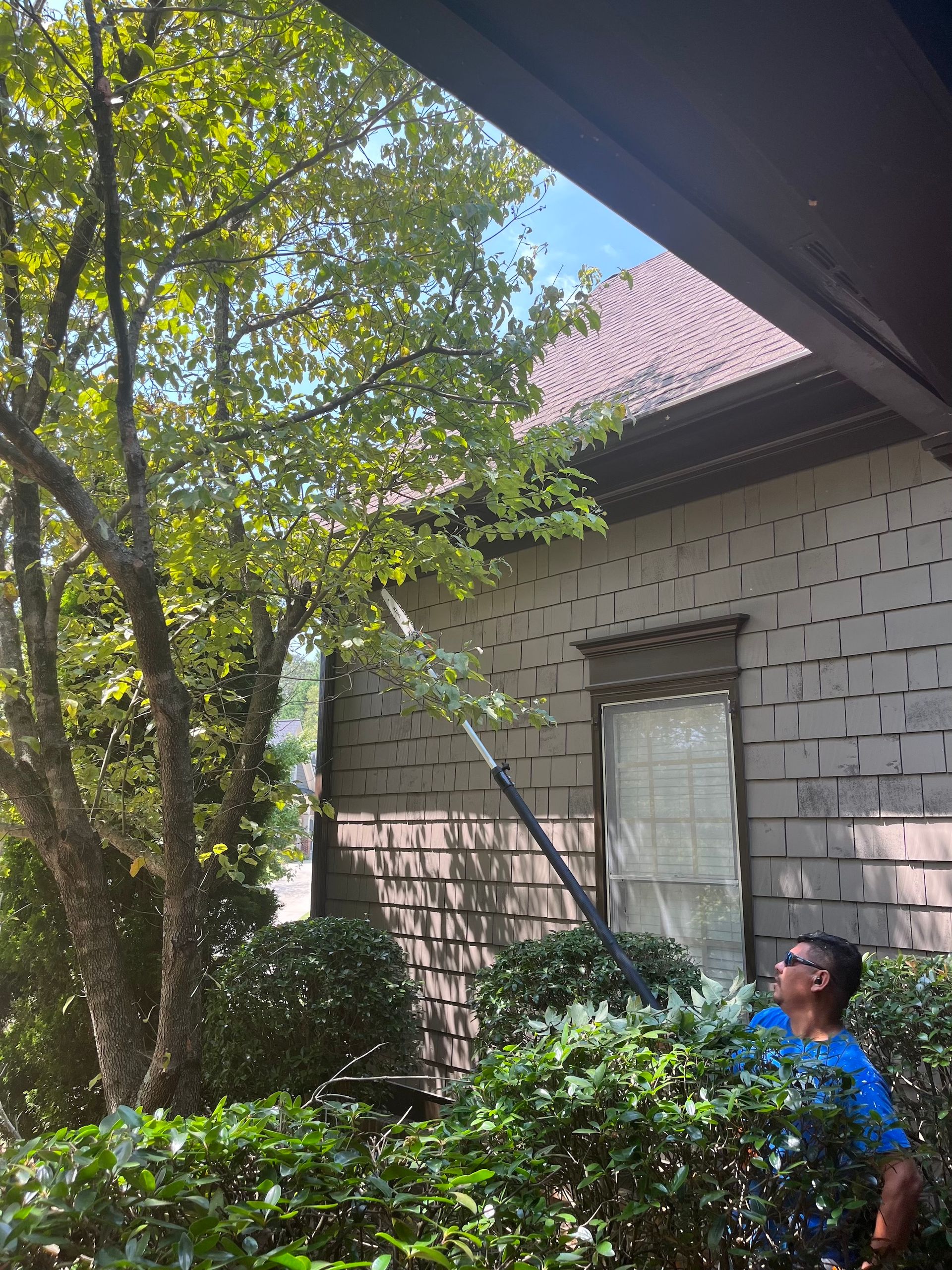 A man is cleaning the gutters of a house with a hose.