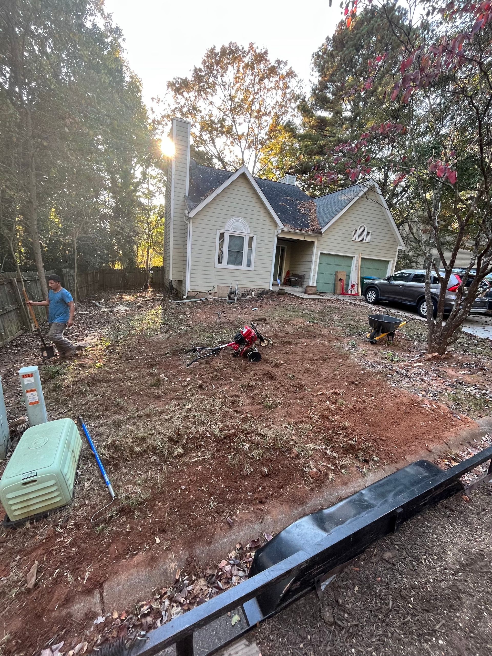 A man is standing in the dirt in front of a house.