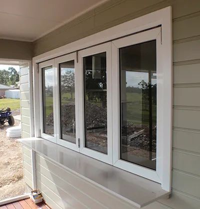 A White Window With a Shelf Underneath It on the Side of a House — Patterson Glass Works in Kempsey, NSW