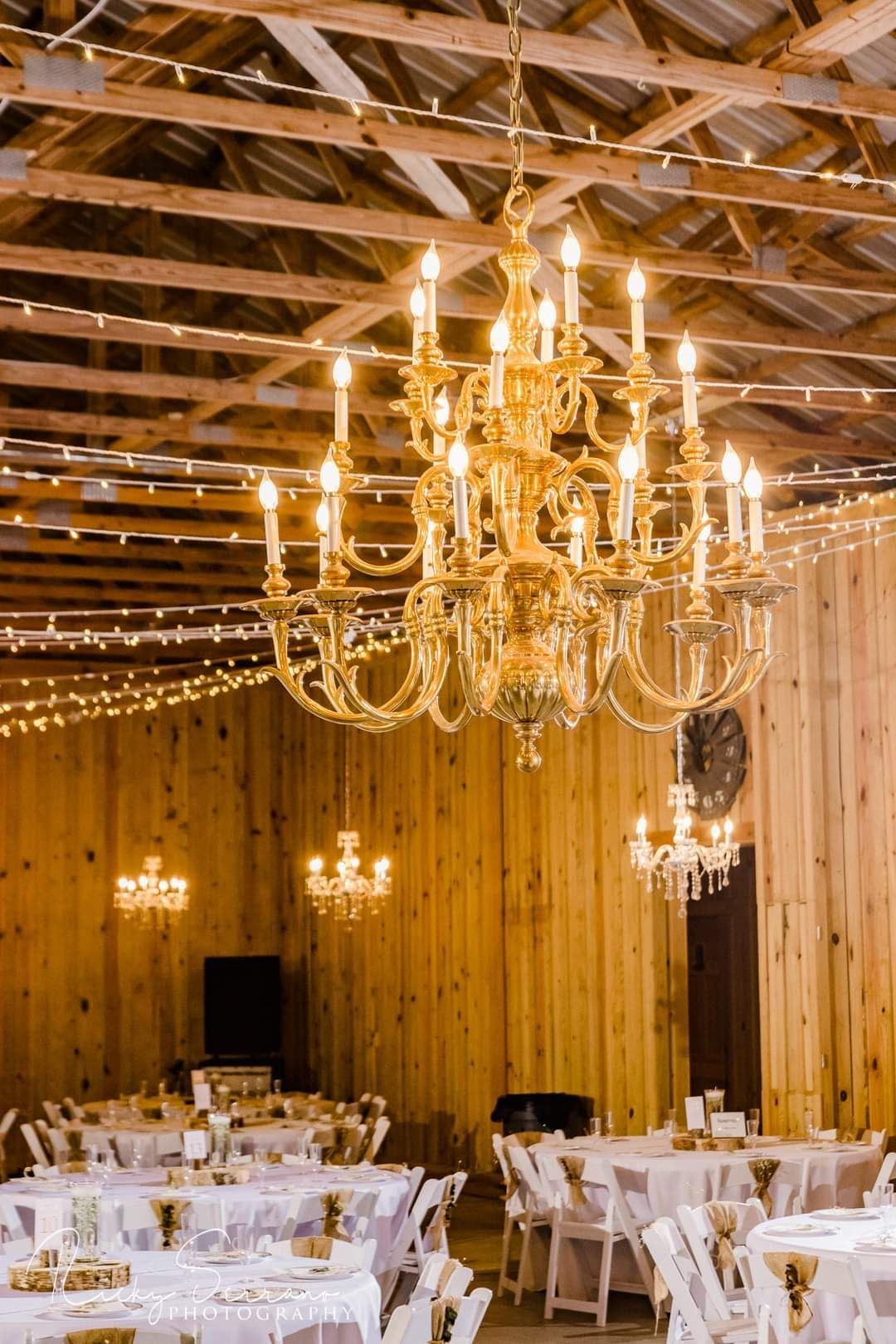 A table set for a wedding reception with plates , glasses , and a vase of flowers.