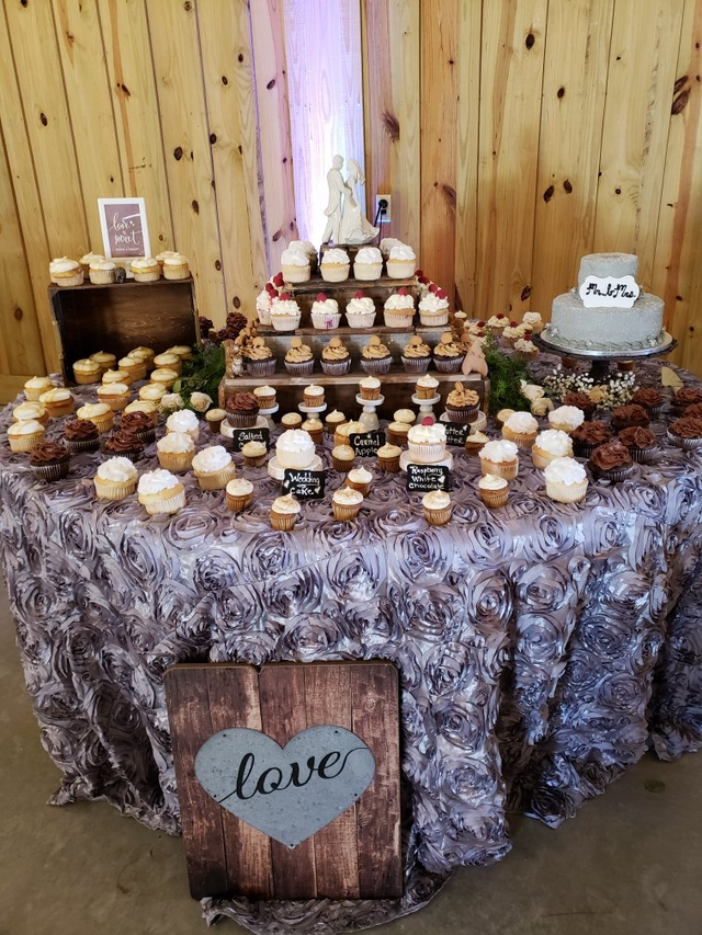 A table topped with cupcakes and a sign that says `` love ''.