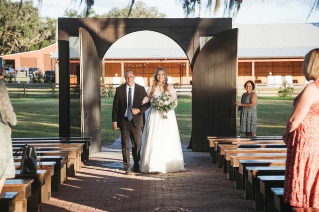 A bride and her father are walking down the aisle at a wedding.