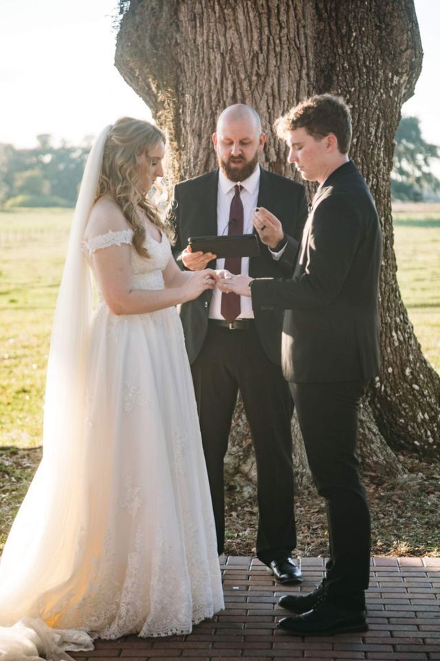 A bride and groom are getting married in front of a tree.