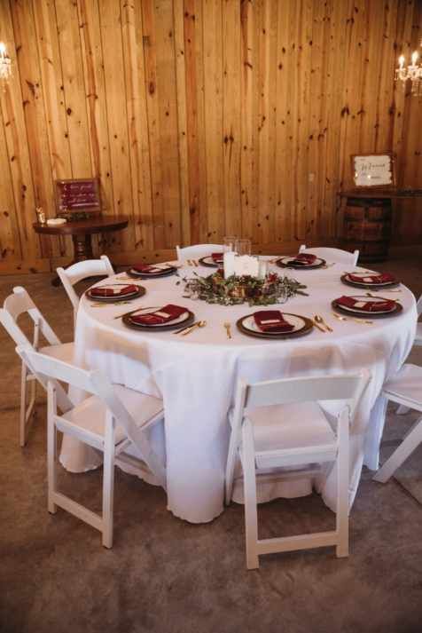 A round table with plates and napkins on it in a room with wooden walls.