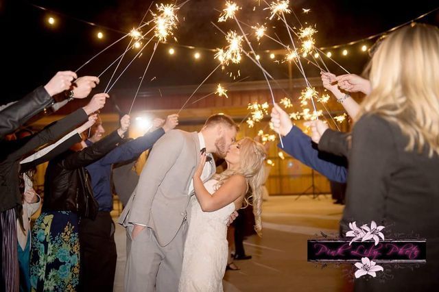 A bride and groom kissing while holding sparklers at their wedding reception.