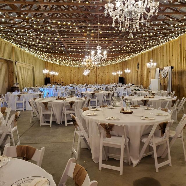 A large room with tables and chairs set up for a wedding reception