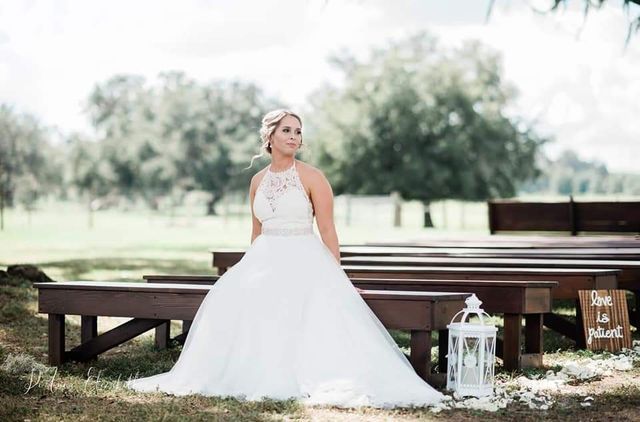 A bride in a wedding dress is sitting on a wooden bench.