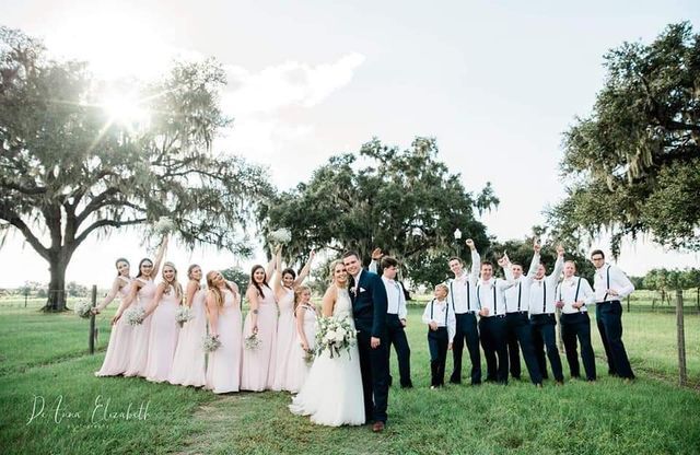 A bride and groom are posing for a picture with their wedding party.