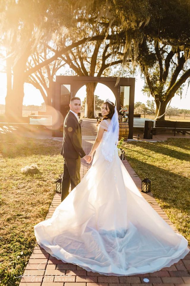 A bride and groom are standing next to each other on a brick walkway holding hands.