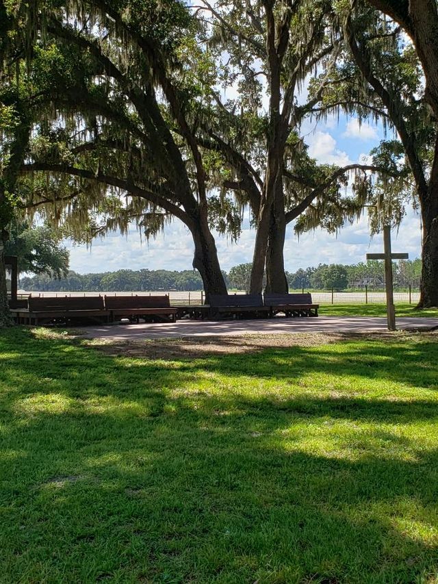 There is a cross in the middle of a park surrounded by trees.