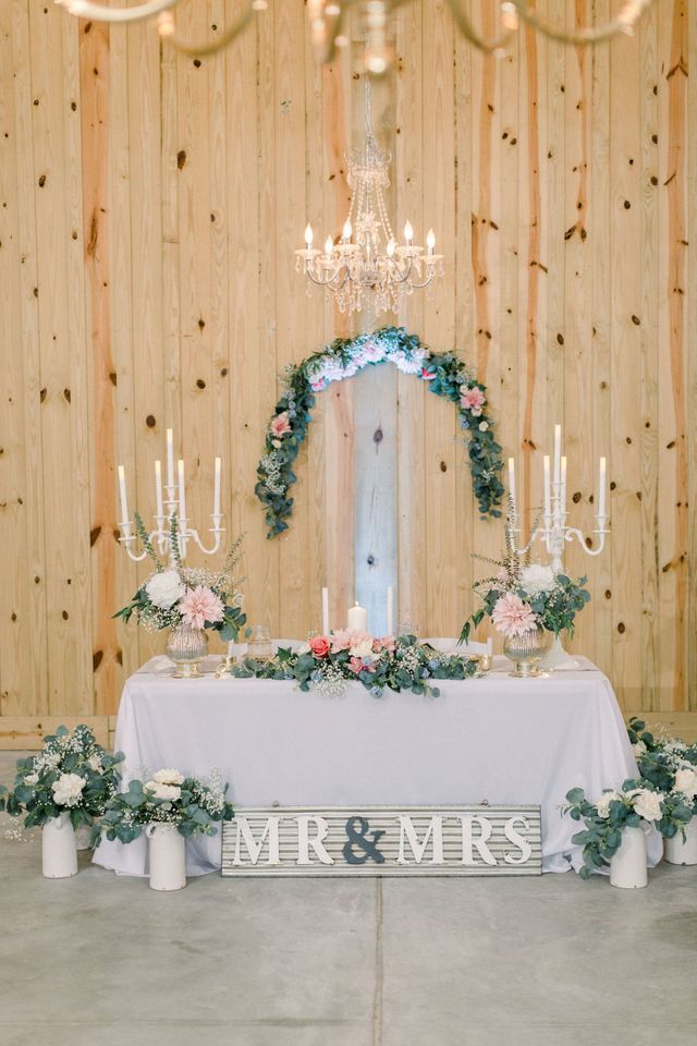 A table with flowers and candles on it in front of a wooden wall.