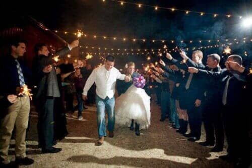 A bride and groom are walking through a tunnel of sparklers.