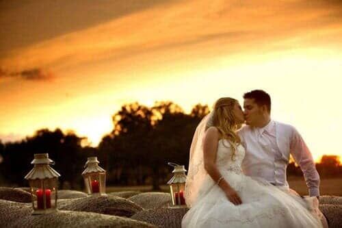 A bride and groom are kissing in front of a sunset.