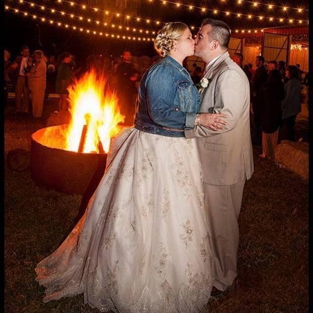 A bride and groom kissing in front of a fire pit