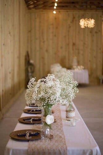 A long table with a vase of baby 's breath on it.
