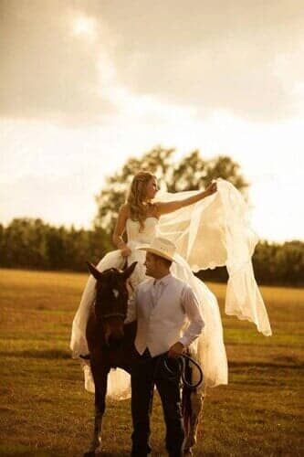 A bride and groom are standing next to a horse in a field.