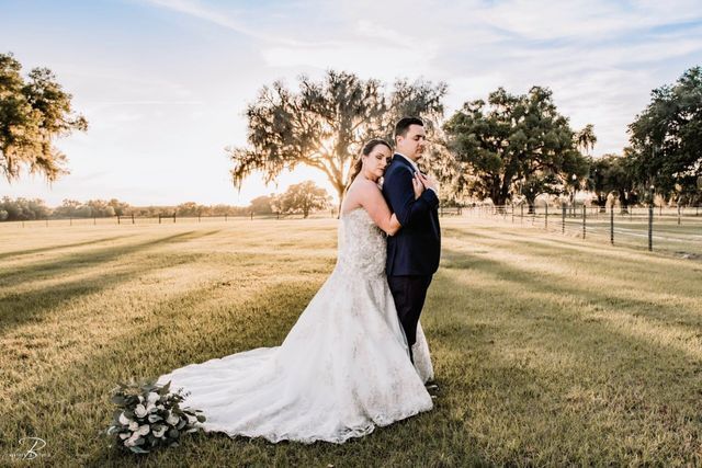 A bride and groom are posing for a picture in a field.