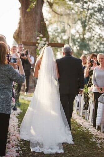 A bride and her father are walking down the aisle at a wedding.