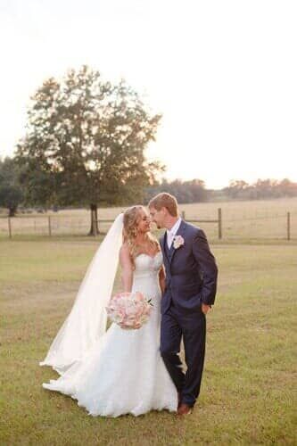 A bride and groom are kissing in a field.