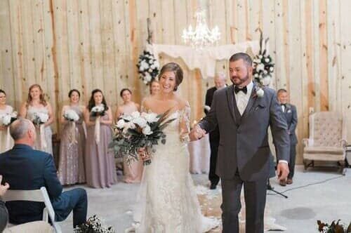 A bride and groom are walking down the aisle at their wedding holding hands.