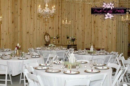 A large room with tables and chairs set up for a wedding reception.