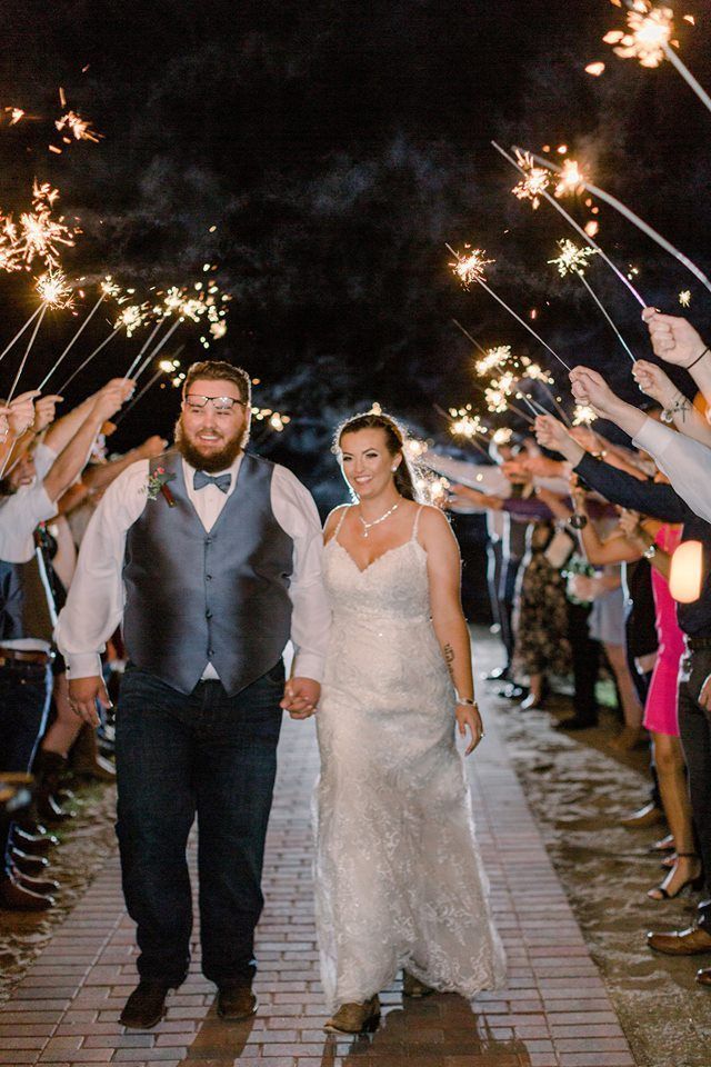 A bride and groom are walking through a tunnel of sparklers.