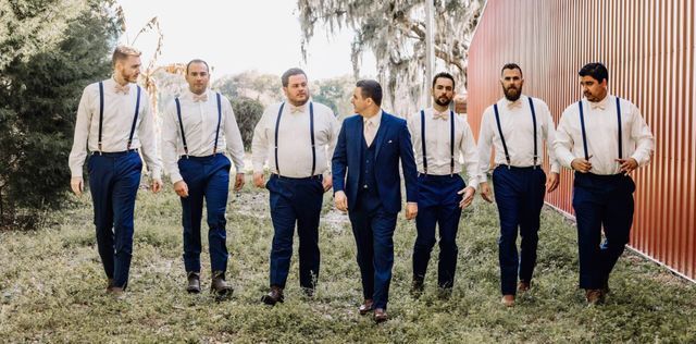 A groom and his groomsmen are walking in a field.