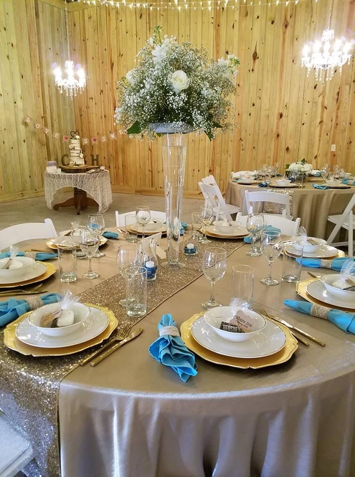 A table set for a wedding reception with plates , glasses , napkins and a vase of flowers.