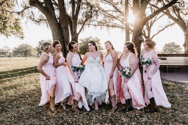 A bride and her bridesmaids are posing for a picture in a field.