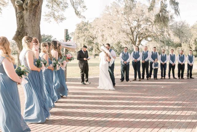 A bride and groom are getting married in front of their wedding party.