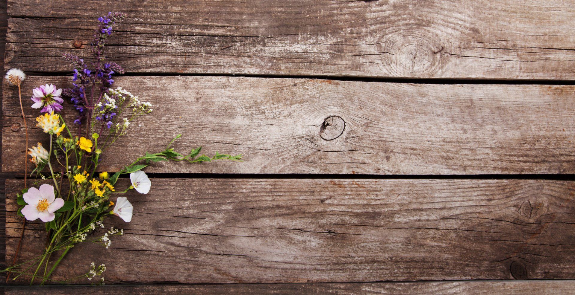 A bouquet of flowers is sitting on a wooden table.