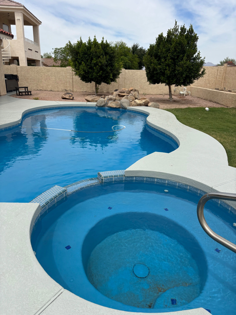 Backyard swimming pool with attached hot tub, light blue deck, and desert landscaping