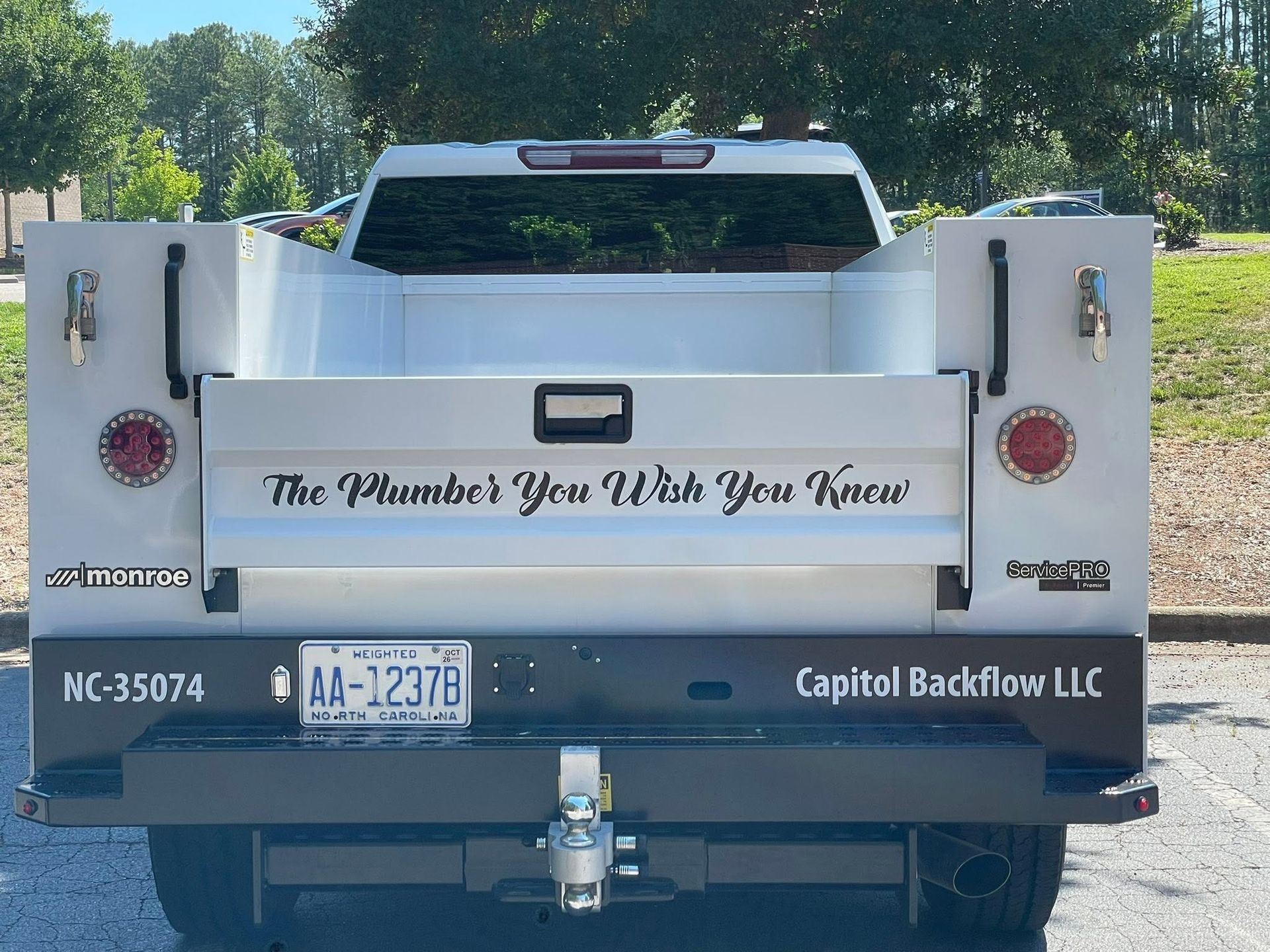 Rear of a white Capital Backflow LLC truck with service doors open and “The Plumber You’ll Wish You Knew” text