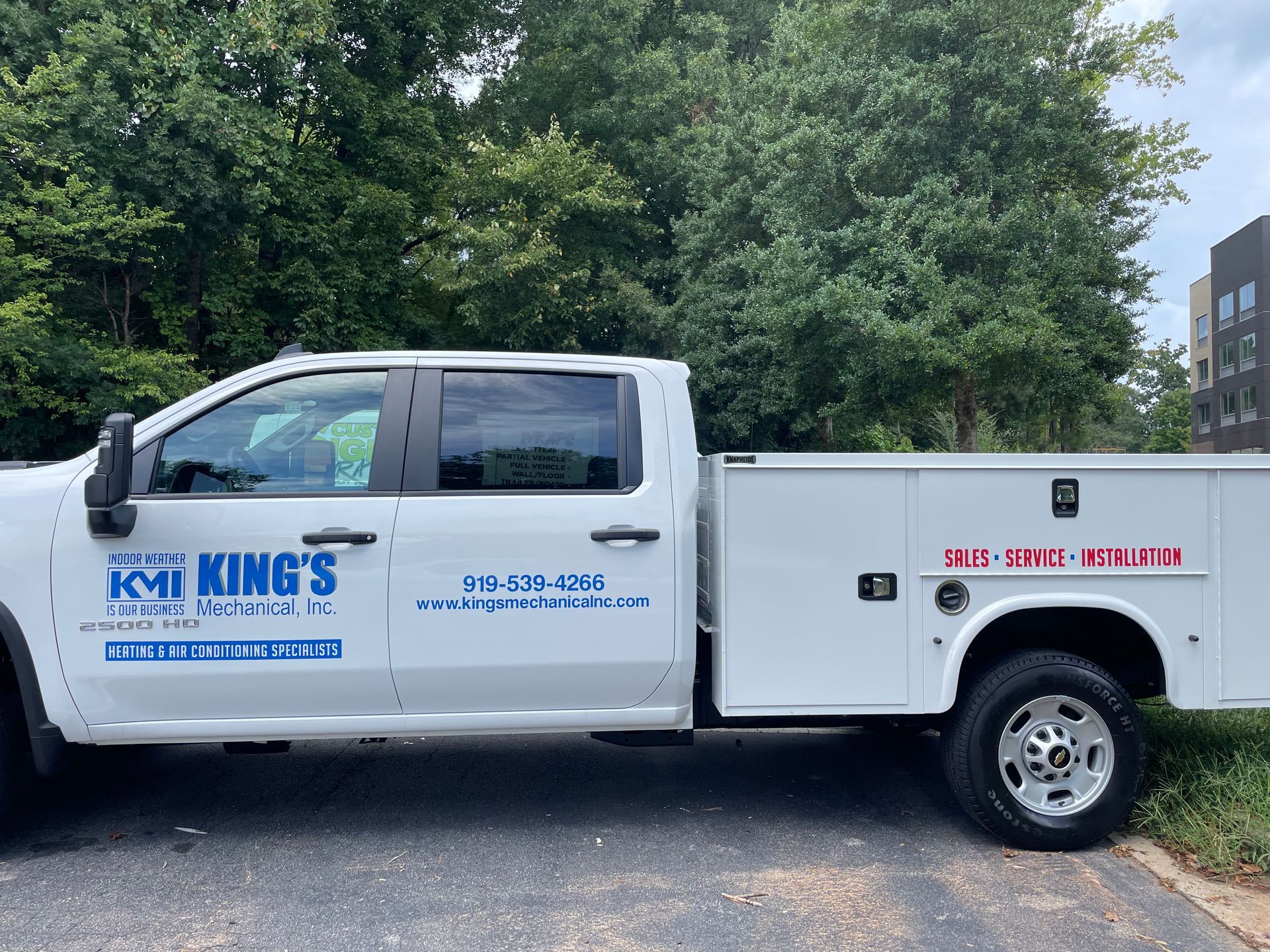 White King’s service truck parked on grass beside trees and a building.
