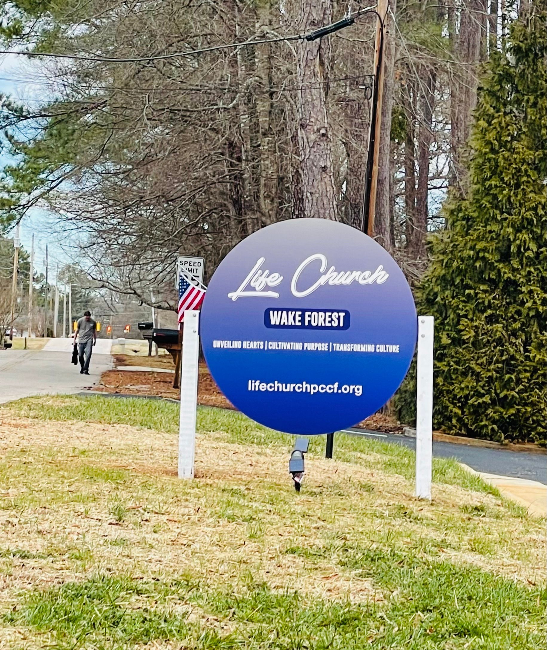 Outdoor sign for “Lynx Creek” with blue and purple background along a roadside
