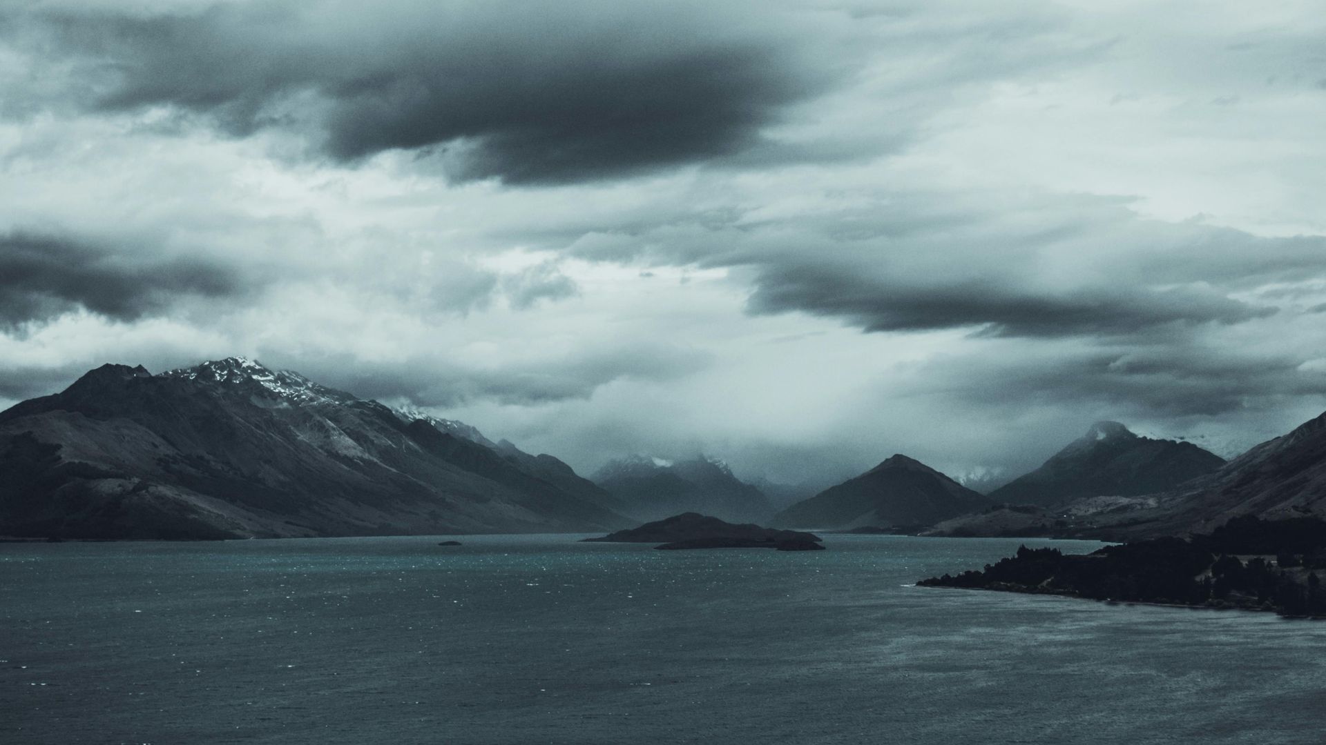 A black and white photo of a lake with mountains in the background.