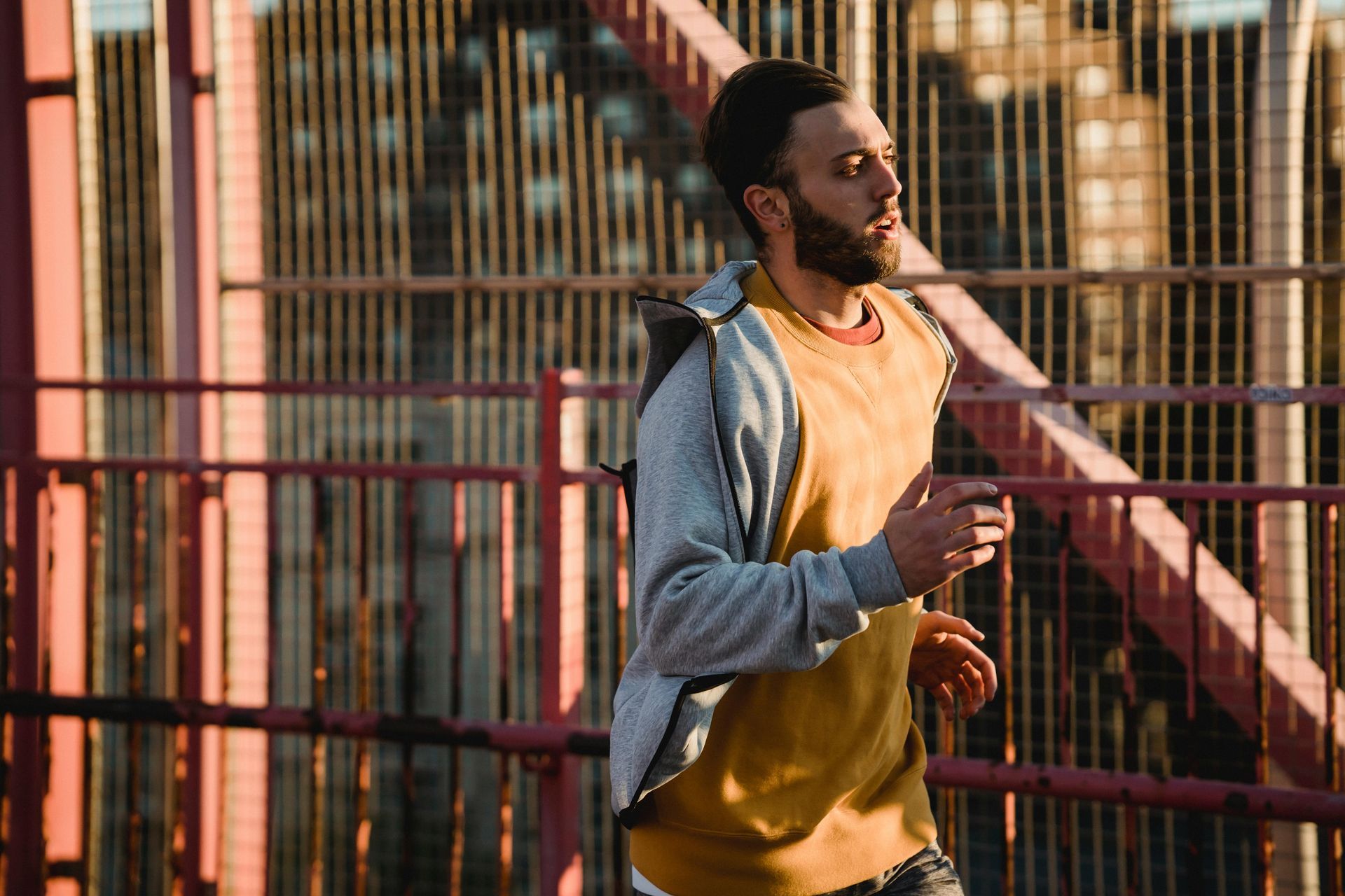 A man with a beard is running on a bridge.