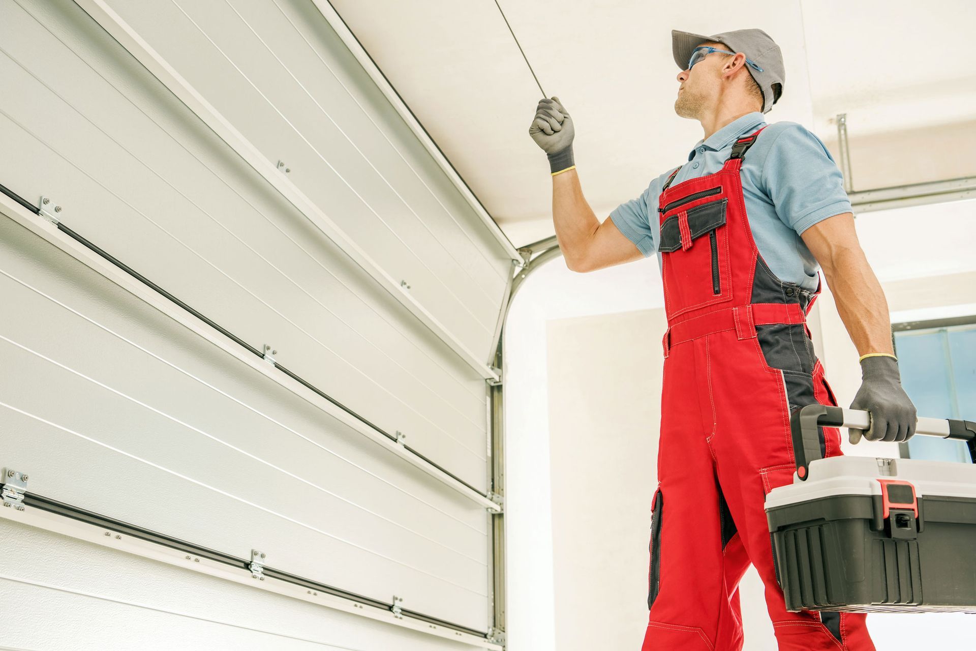 A worker is checking that the garage door works properly after the installation.