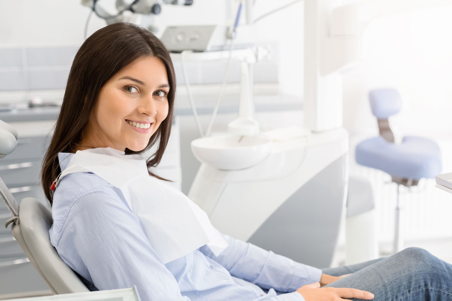 Smiling woman in a dental chair inside a bright modern clinic Smiling woman in a dental chair inside a bright modern clinic