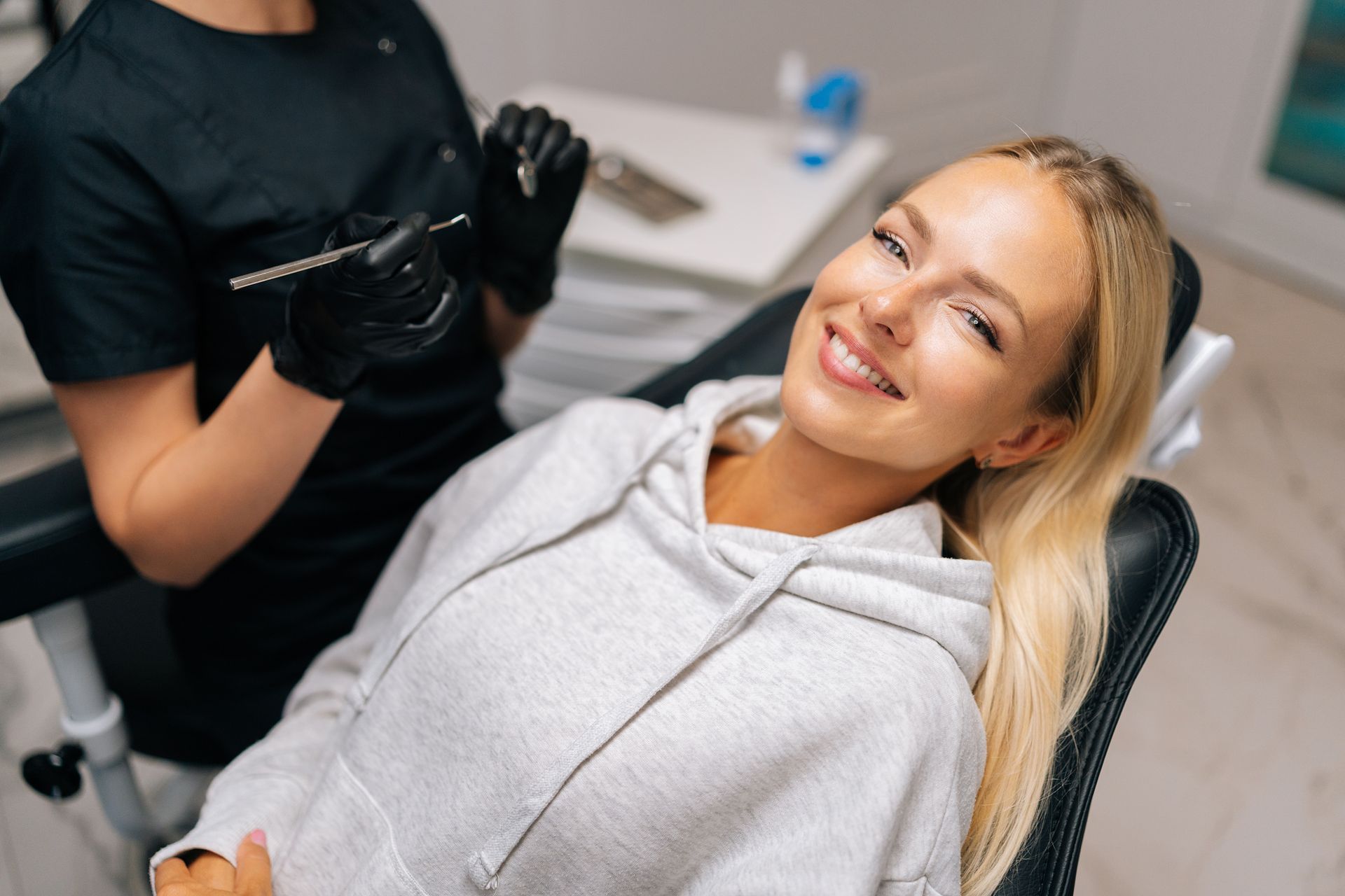 Woman smiling in a dental chair during a checkup with a clinician nearby