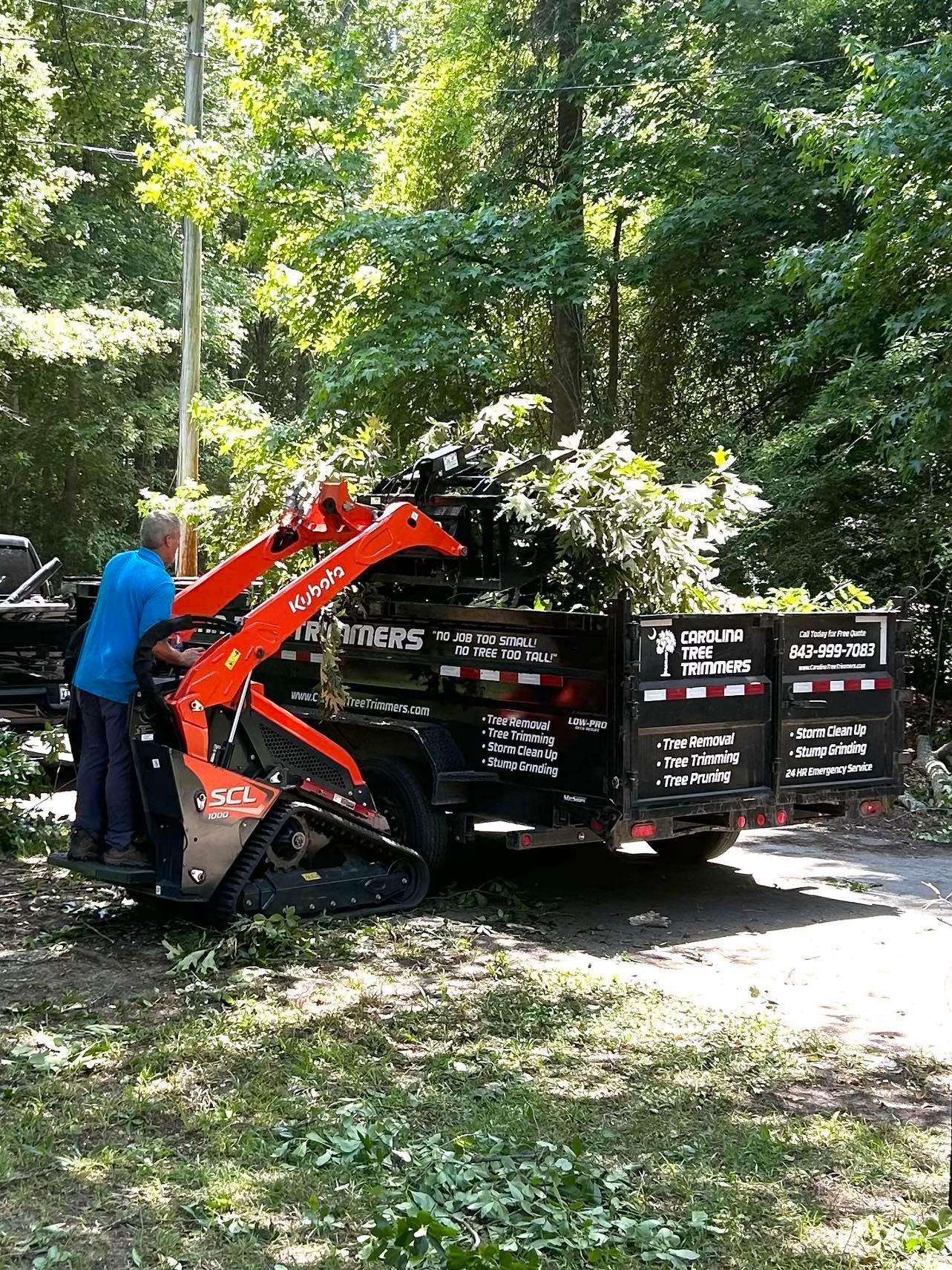 A green crane is cutting a tree in front of a house
